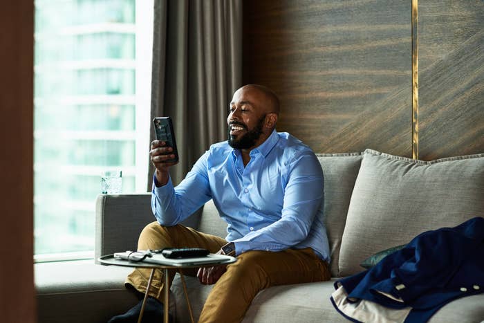 Man sits on couch while looking at phone