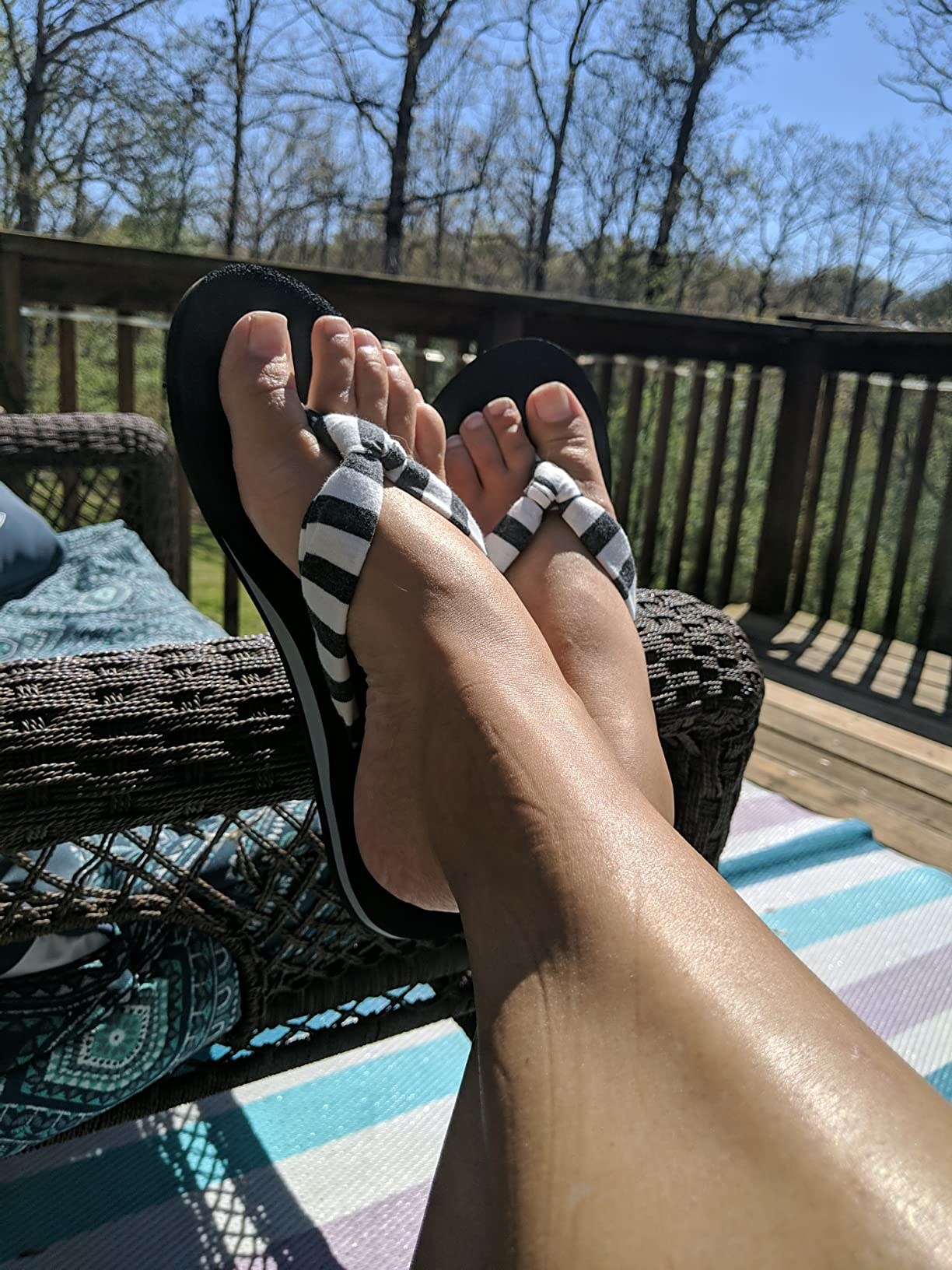 Reviewer with feet kicked up on patio lounge chair wearing black and white striped flip flops