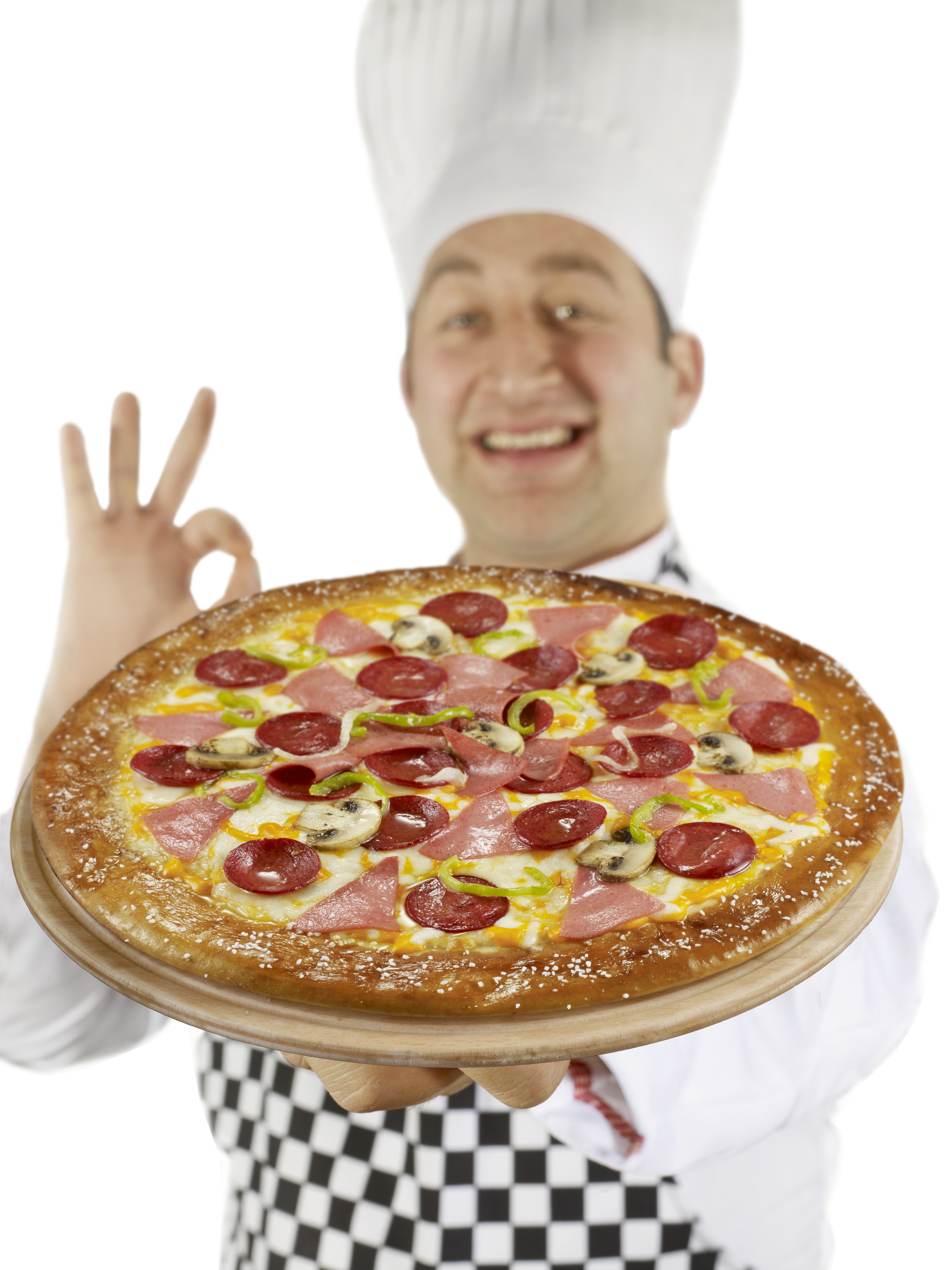 A man in a chef&#x27;s hat holding a large pizza with pepperoni, ham, mushrooms, and peppers