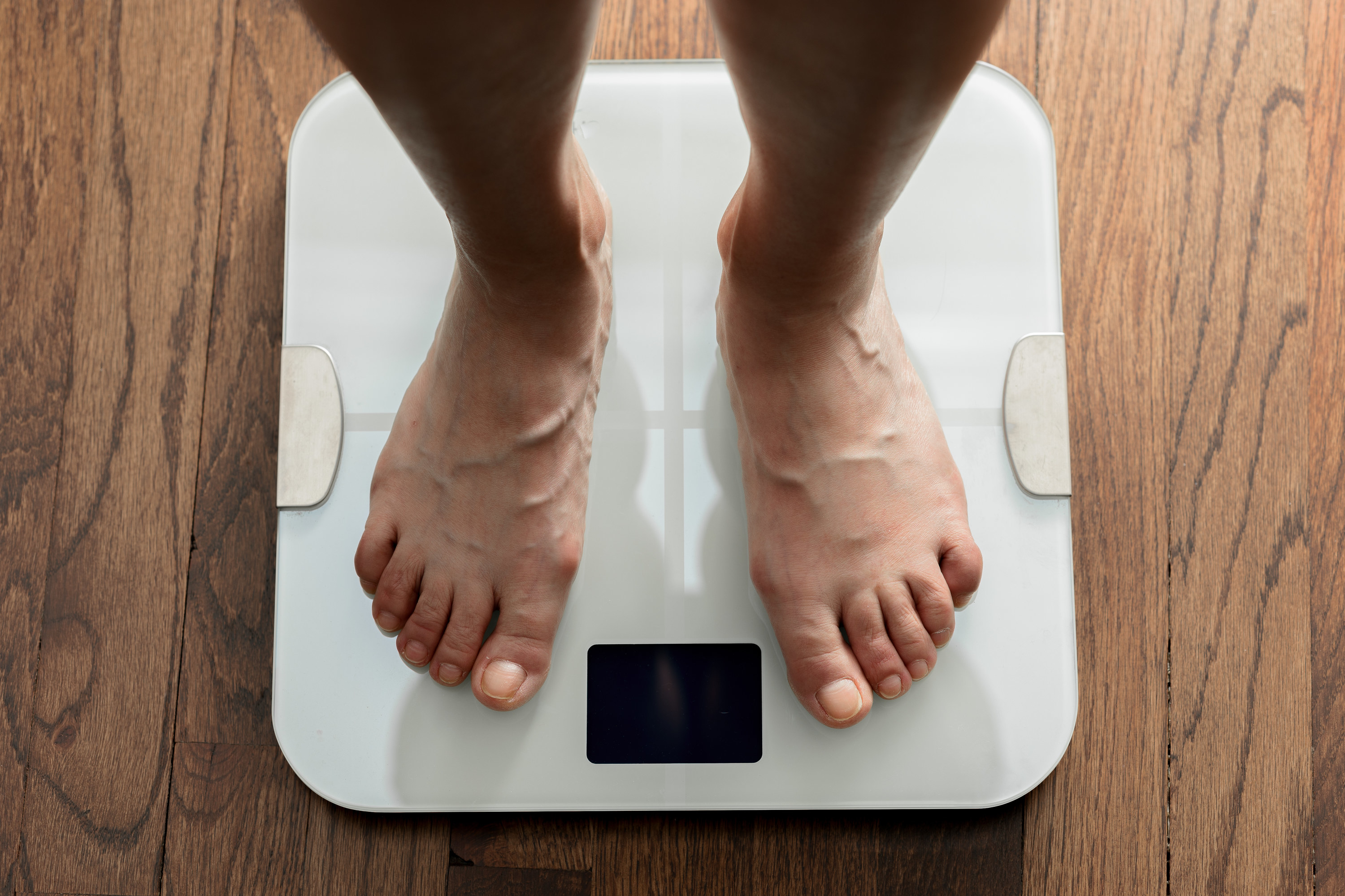 Feet standing on a white bathroom scale