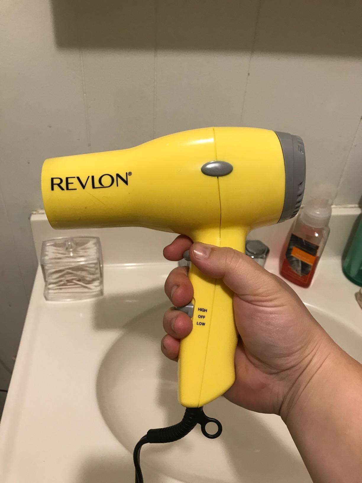 Reviewer holding the yellow Revlon hair dryer