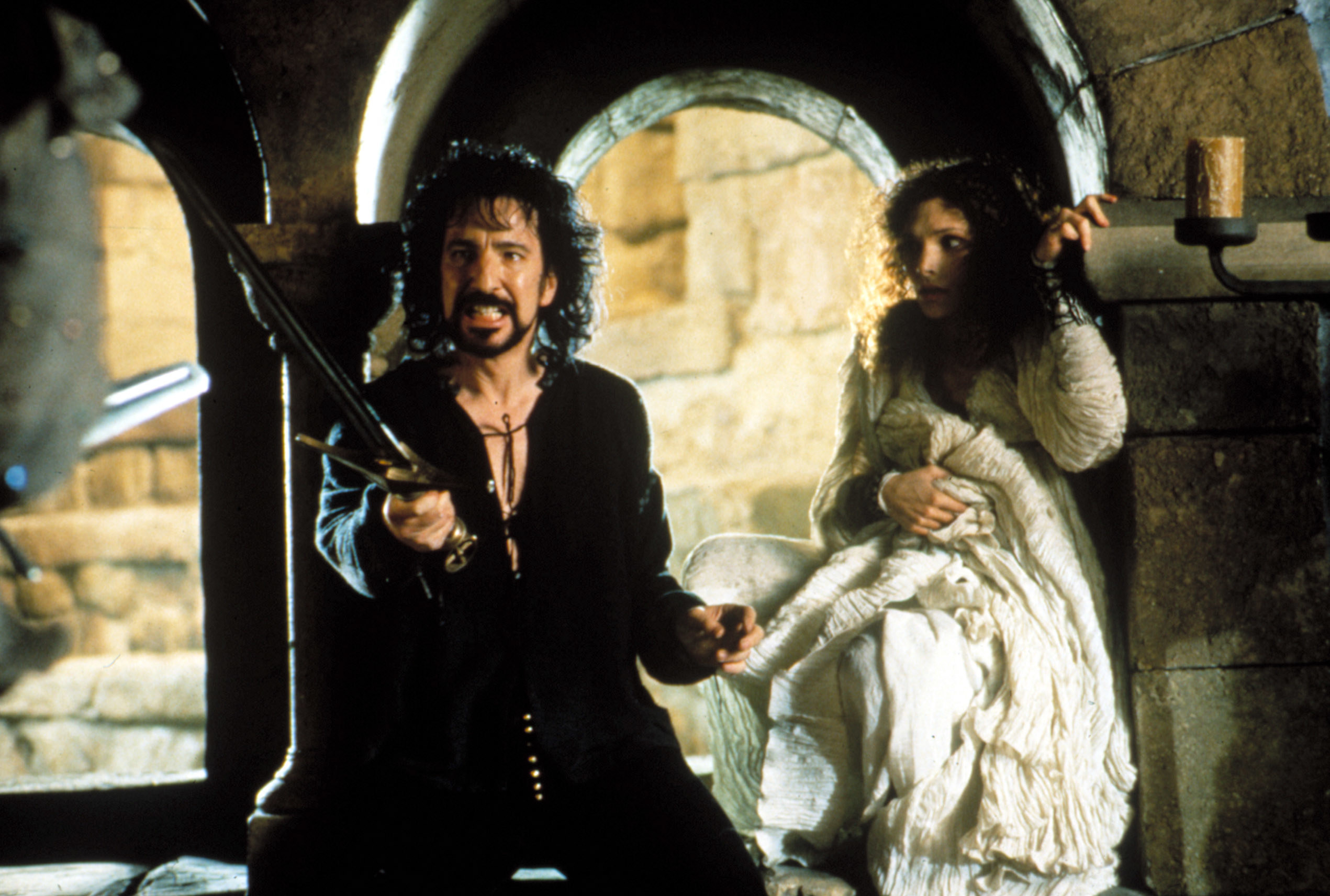 Alan Rickman brandishes a sword while Mary Elizabeth Mastrantonio hids behind him