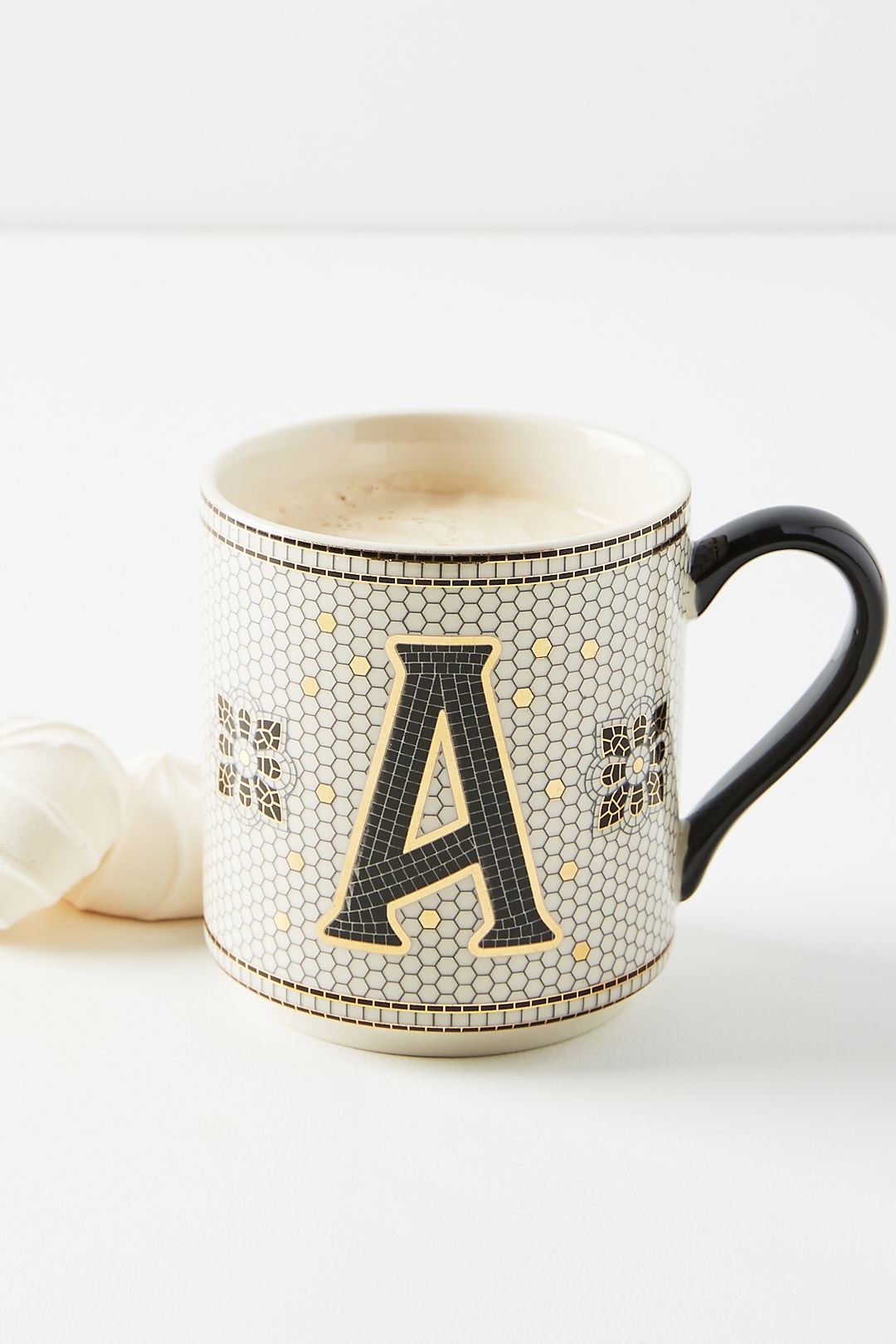 white mug in a black white and gold tiled pattern with a large monogrammed &quot;A&quot;