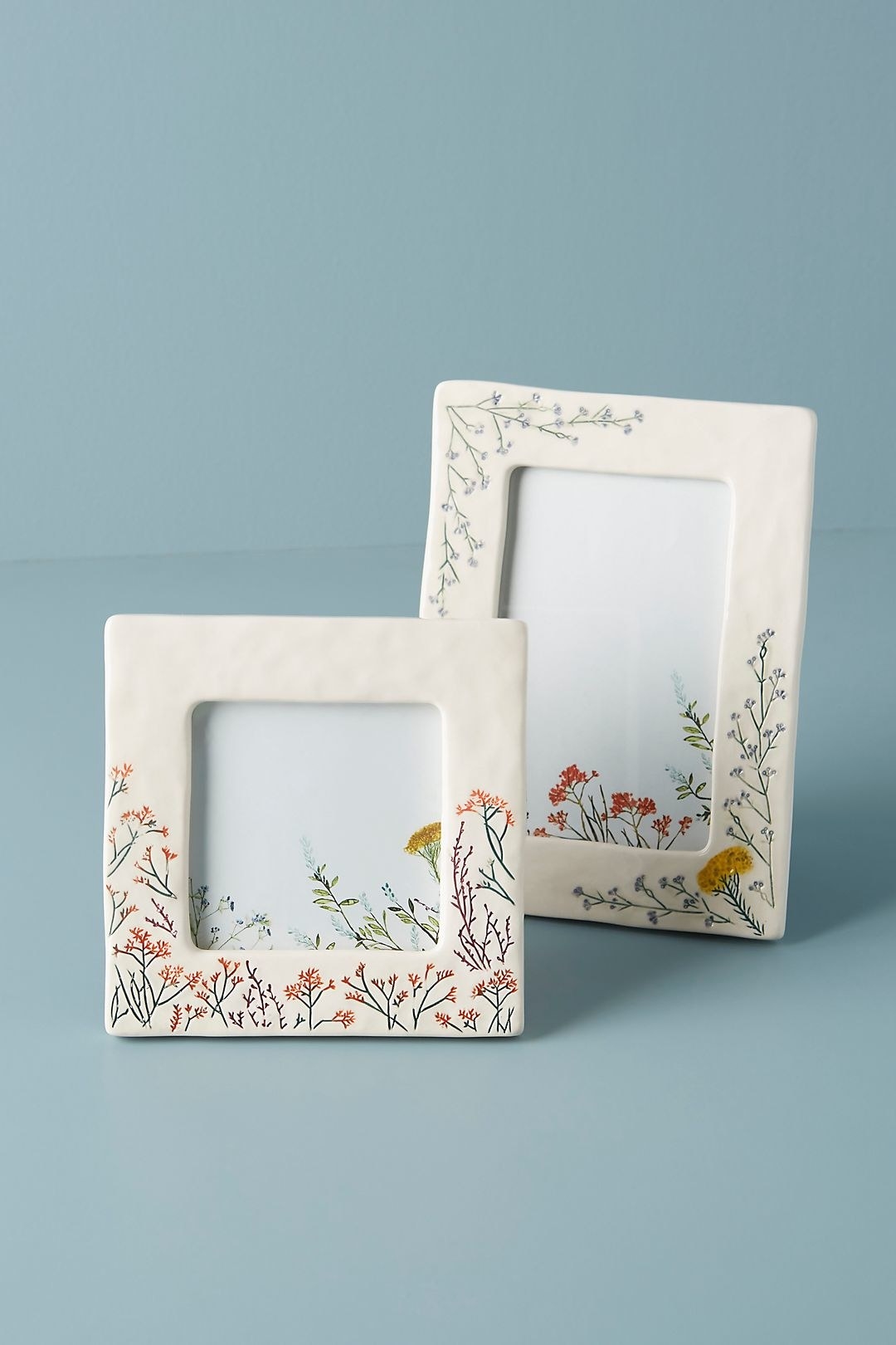 white ceramic picture frames with carved and painted small flowers on them