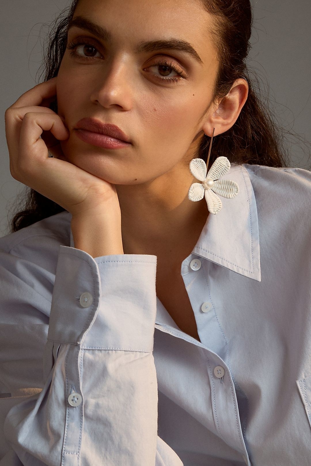 model wearing gold bar drop earrings with sculptural white flowers at the end