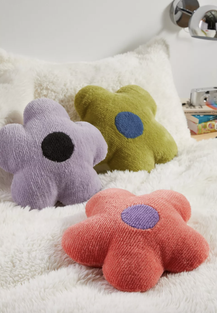 three flower-shaped pillows on a bed