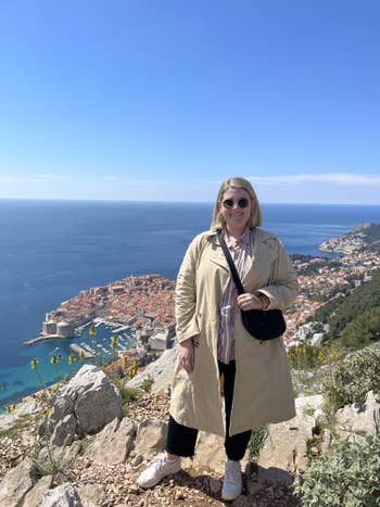 BuzzFeeder standing on a cliff over Dubrovnik wearing a Uniqlo bag