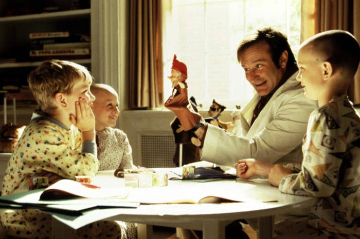 Robin Williams and three kids sitting at a table in Patch Adams