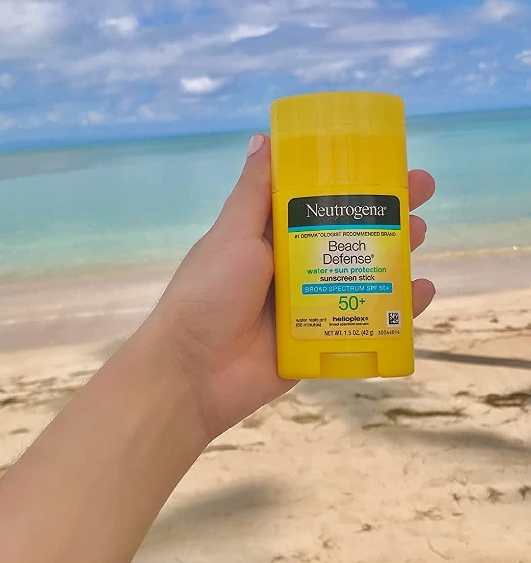 Reviewer holding Neutrogena Beach Defense sunscreen stick