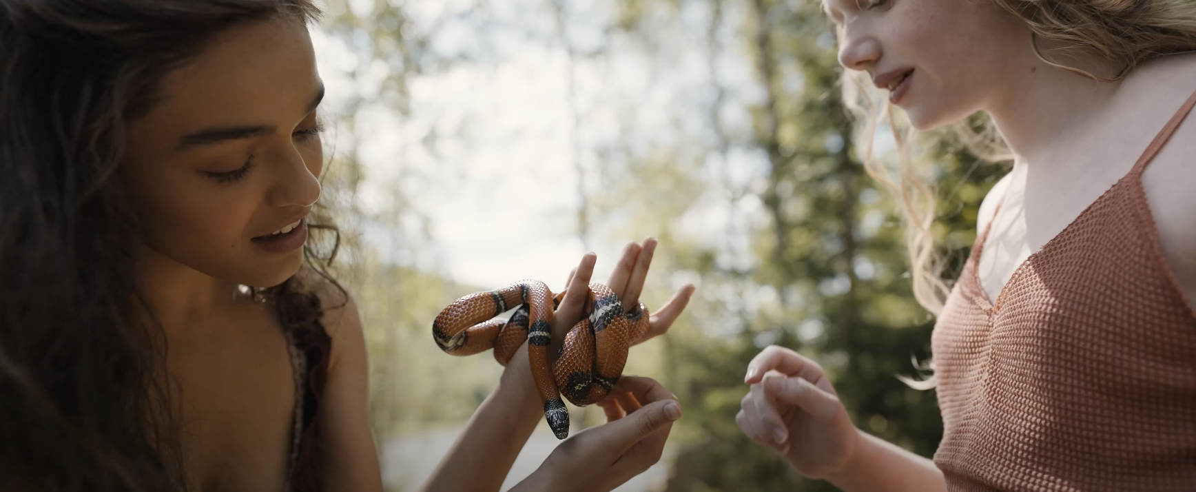 Two women play with a colorful snake