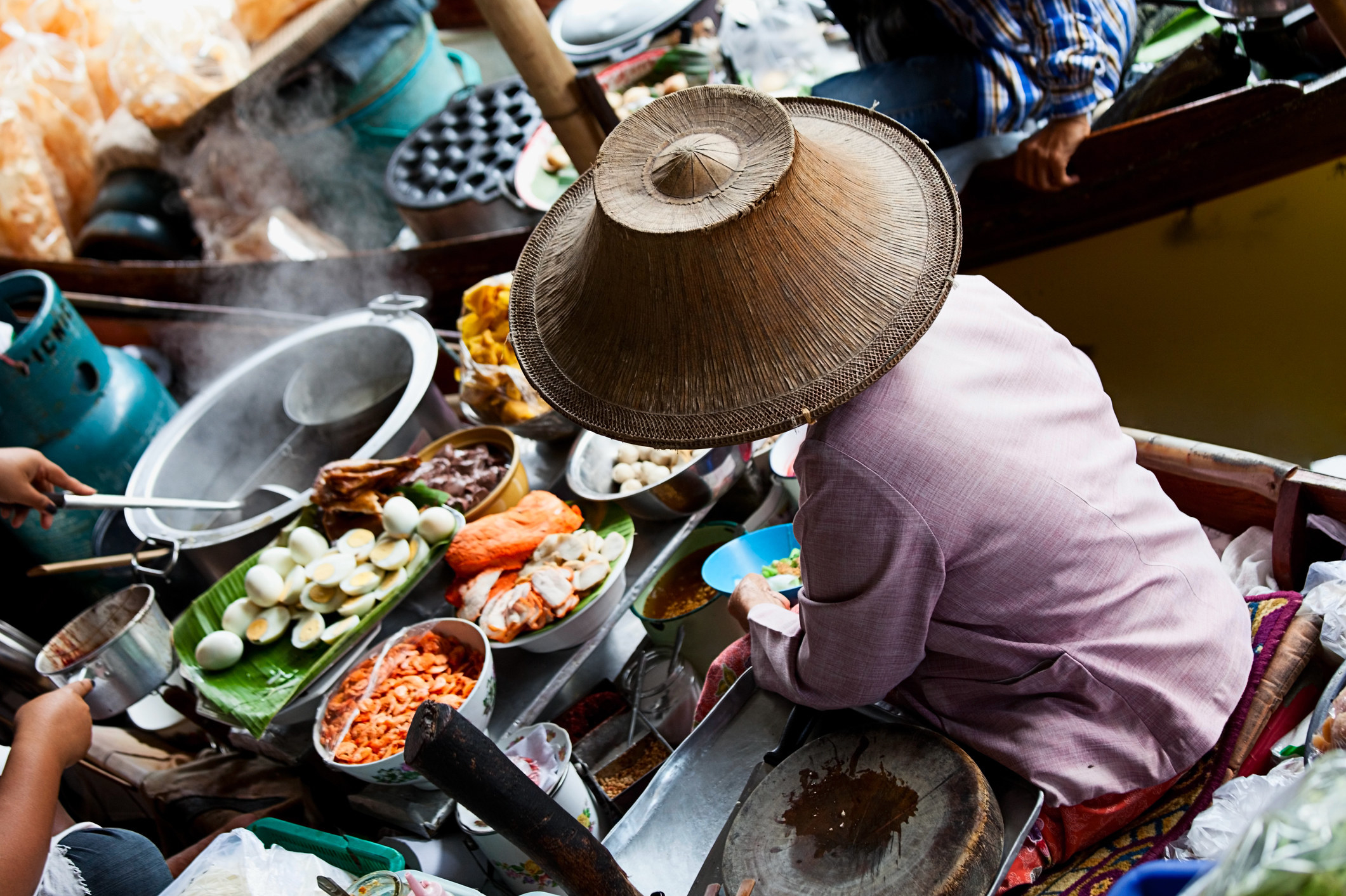 A woman cooking on a boat at a floating food market in Bangkok