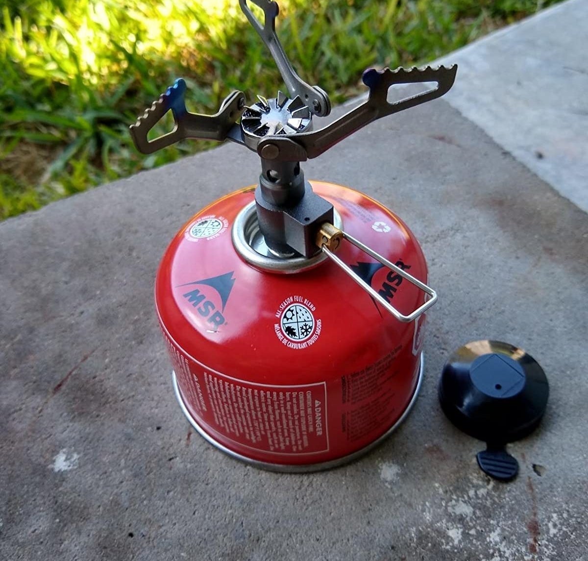 reviewer&#x27;s foldable backpacking stove screwed onto a mini propane canister