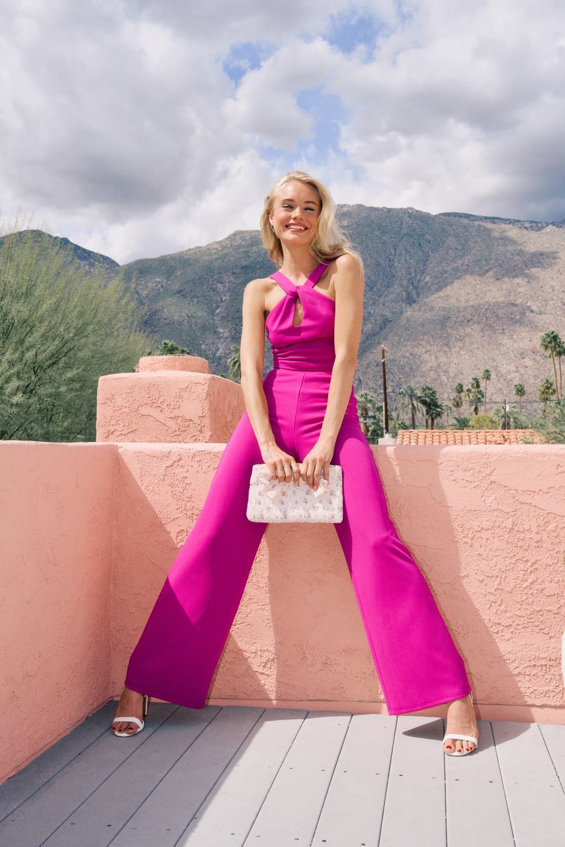 A model wearing a pink jumpsuit and white accessories