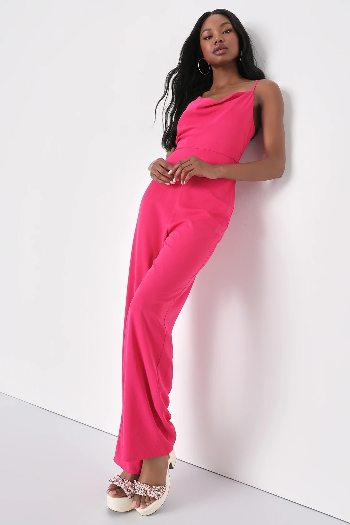 A model in a pink jumpsuit with white shoes