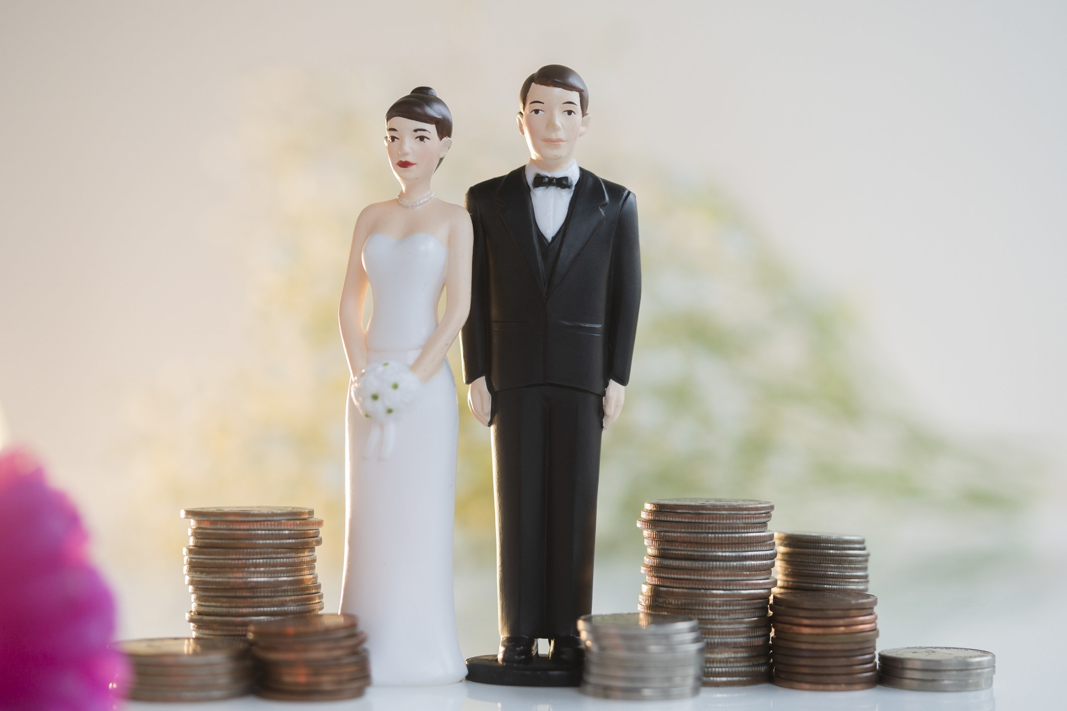 A wedding cake topper couple and stacks of coins