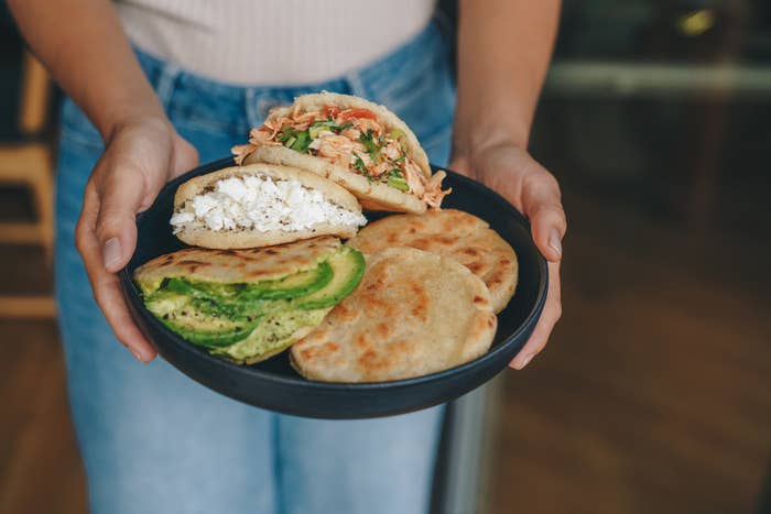 A person carrying a plate of arepas