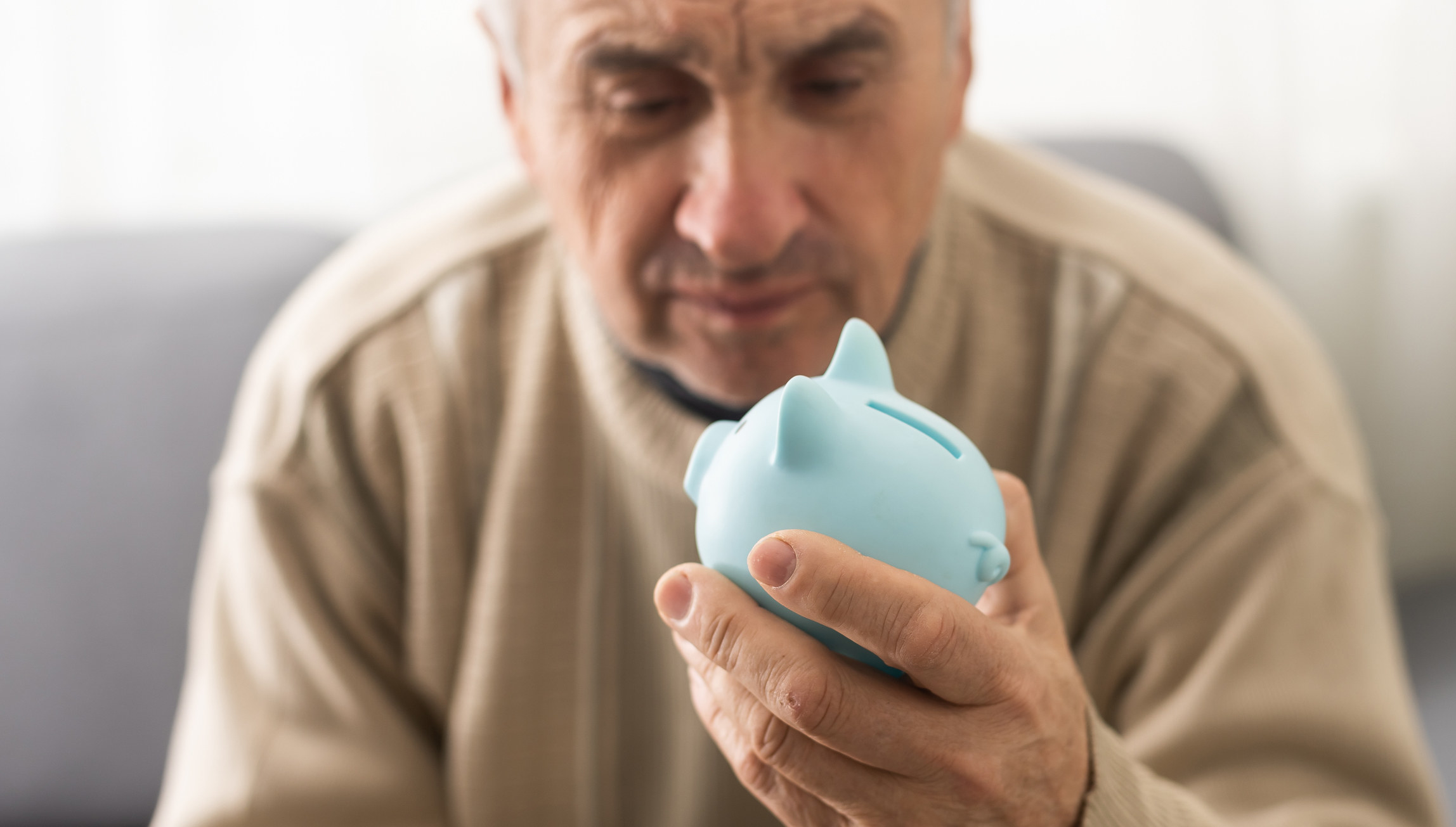 An older man holding a piggy bank