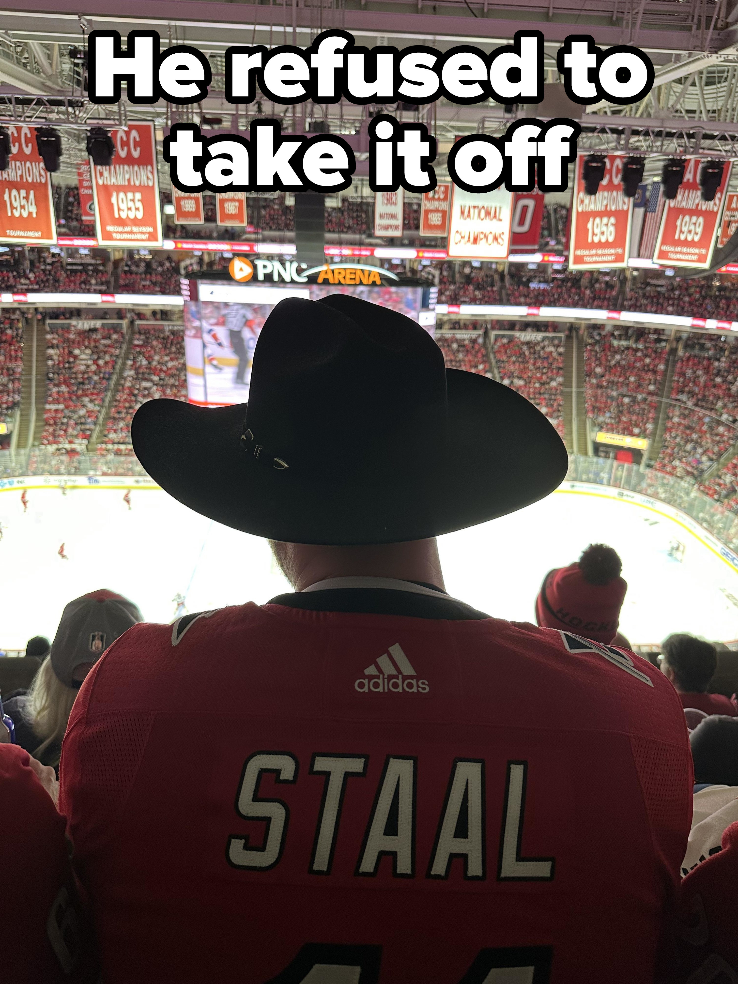 Guy with a cowboy hat at a sports arena blocking a view