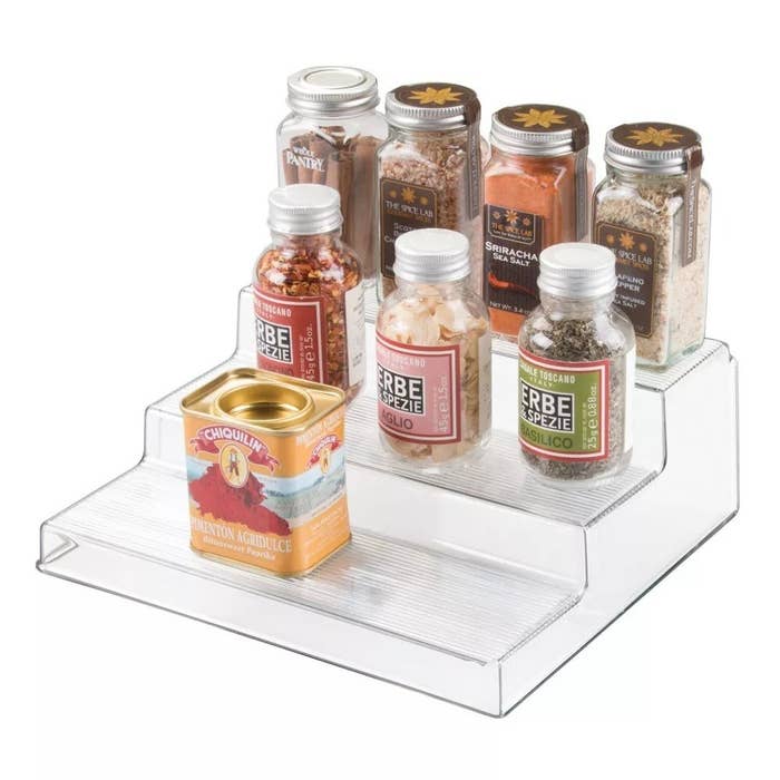 The clear rack with three tiers holding several spices