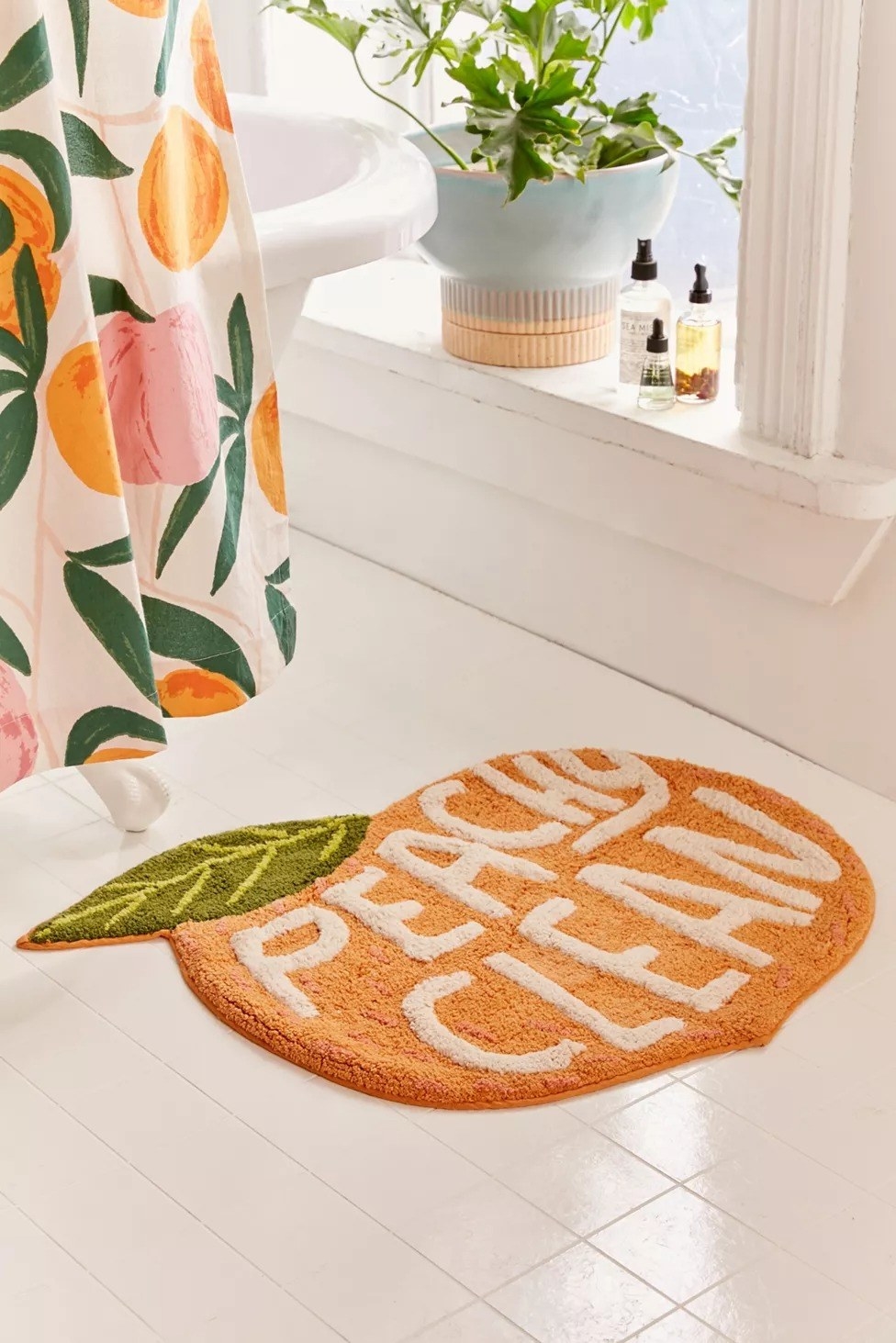 the bath mat on the floor in the shape of a peach that says &quot;peachy clean&quot;