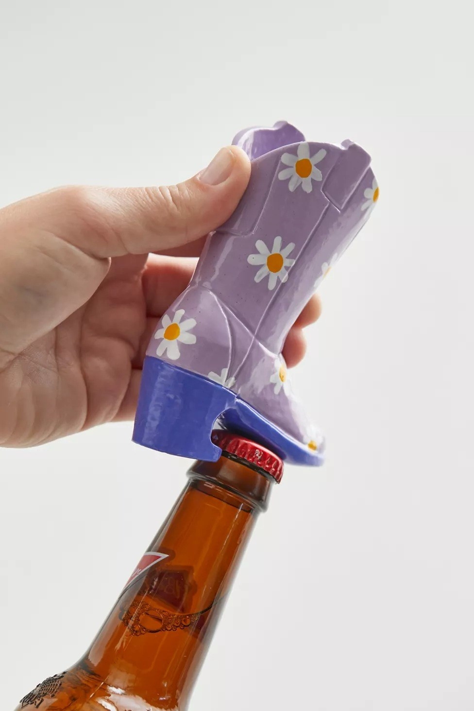 the purple boot with daisies on it being used to open a beer bottle