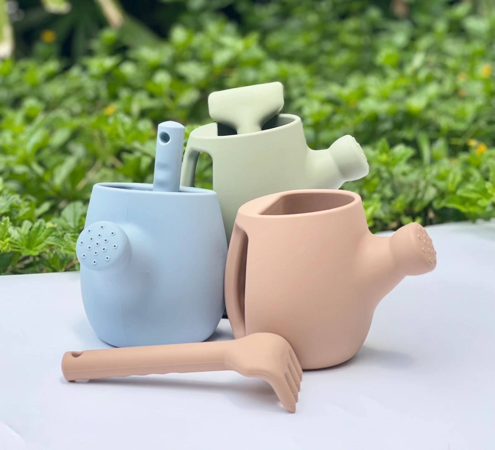 Blue, sage green, and terracotta watering cans and rakes