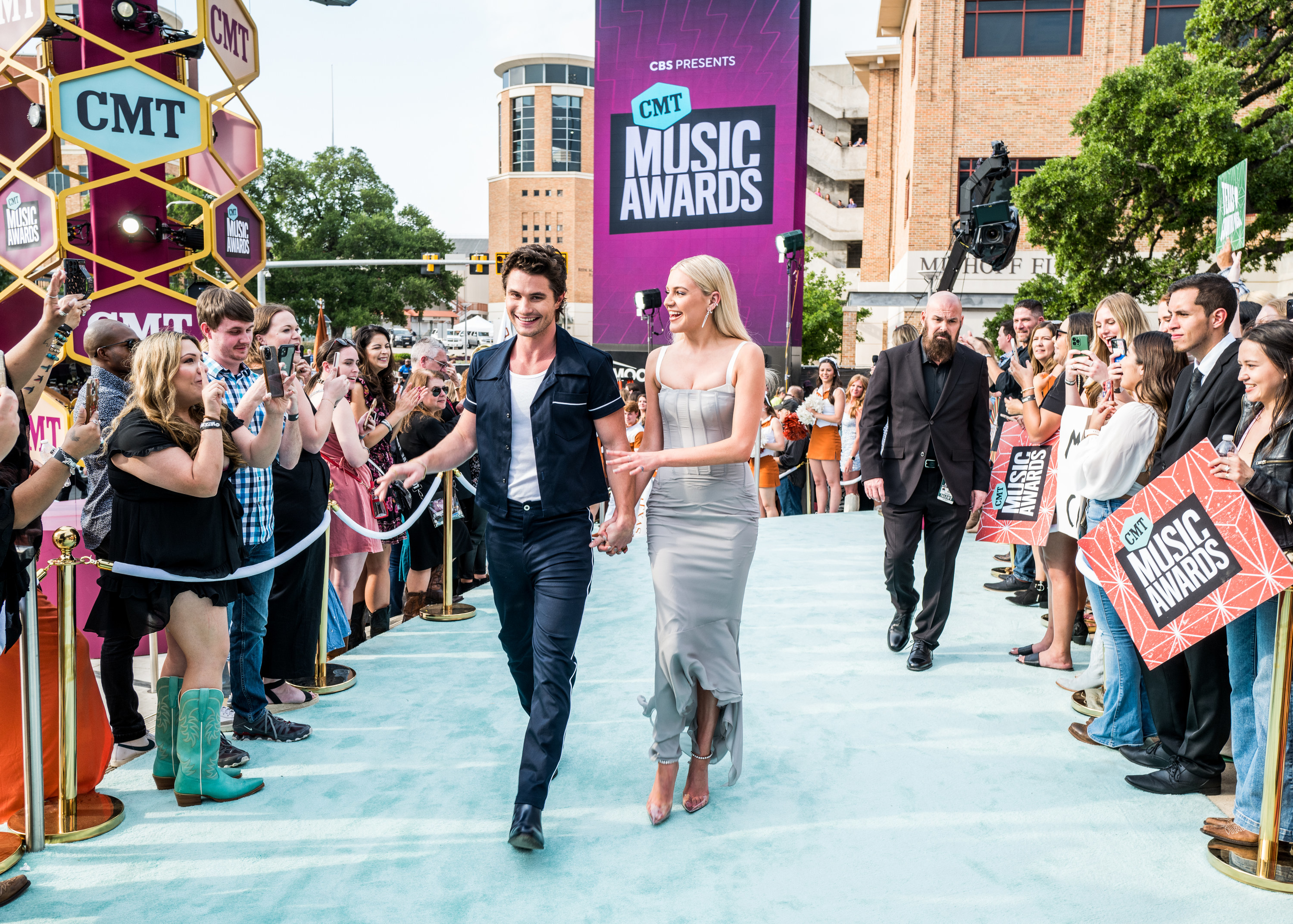 Kelsea and Chase walk through a group of fans on he carpet