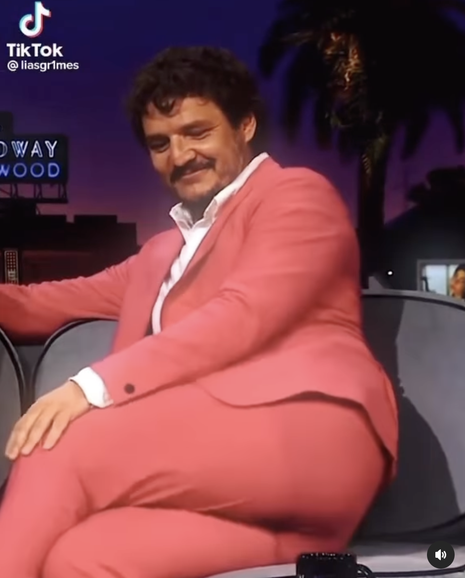 Screenshot from the video of Pedro sitting on a talk show with his legs crossed seductively