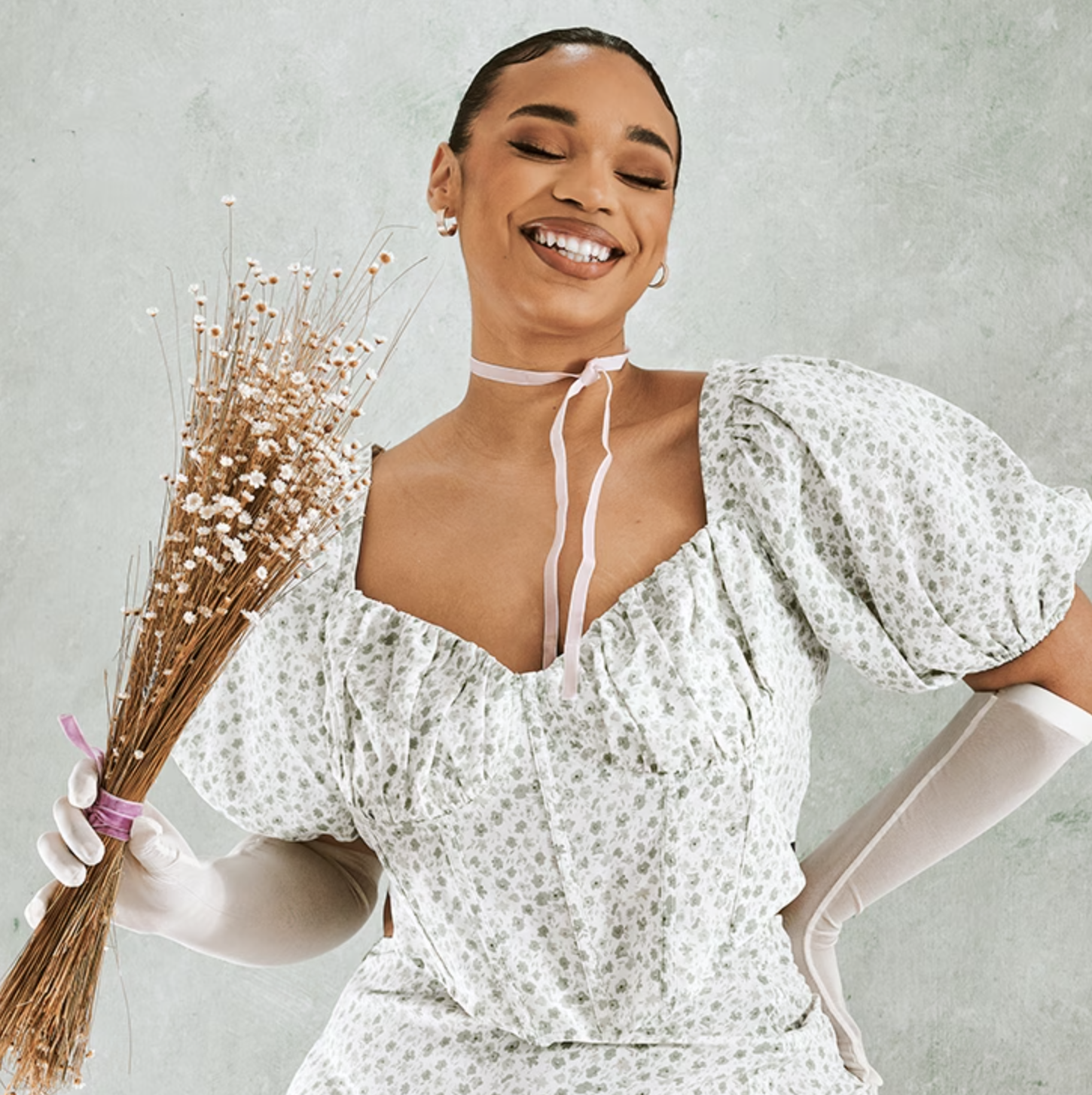 a model wearing the top while holding a dried flower bouqet