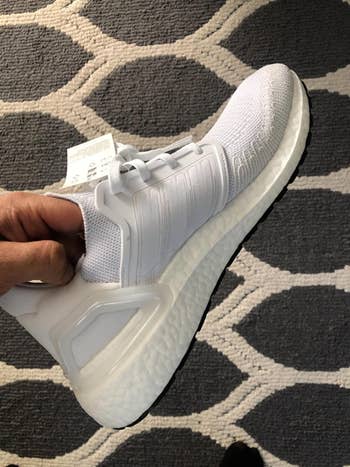 Reviewer holding an Adidas shoe in white