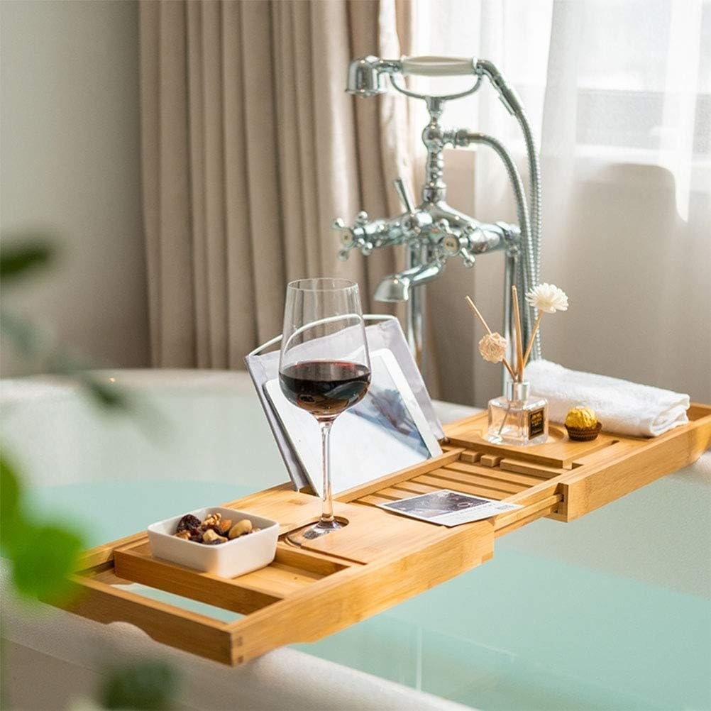 a bamboo bath mat with a bowl of snacks and a glass of wine on top