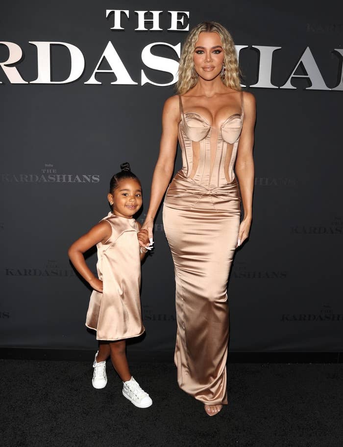 Khloe and True holding hands as they wear matching satin dresses at the premiere of their show
