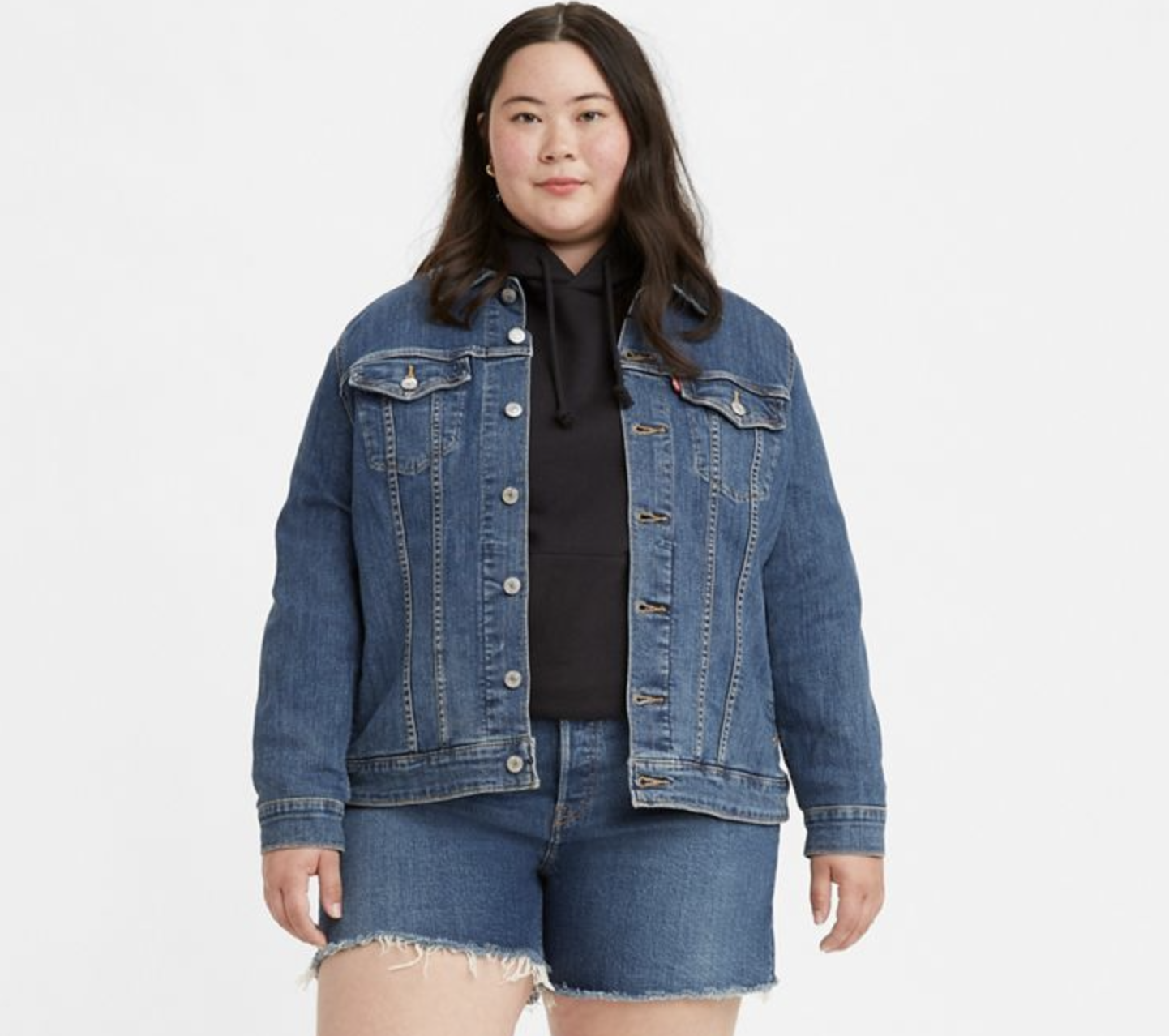 a model wearing the jacket over a sweater and matching denim shorts