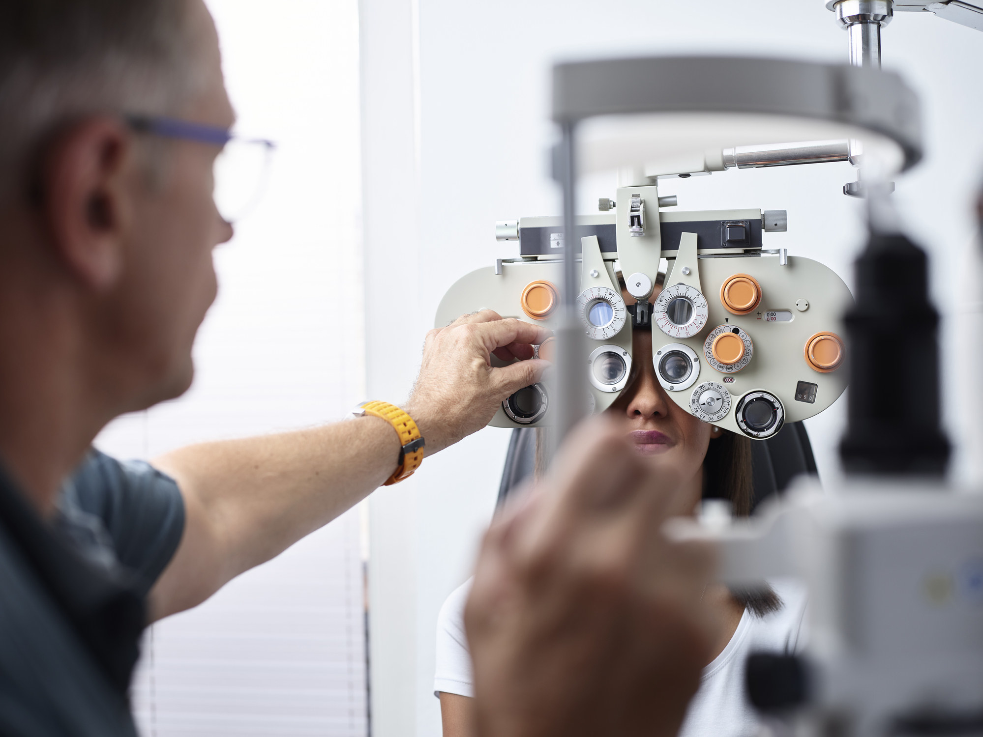 Optometrist examining young woman&#x27;s eyes