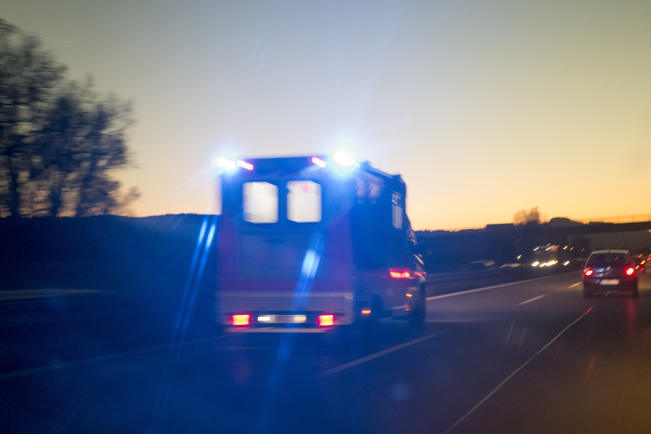 An ambulance driving at dusk