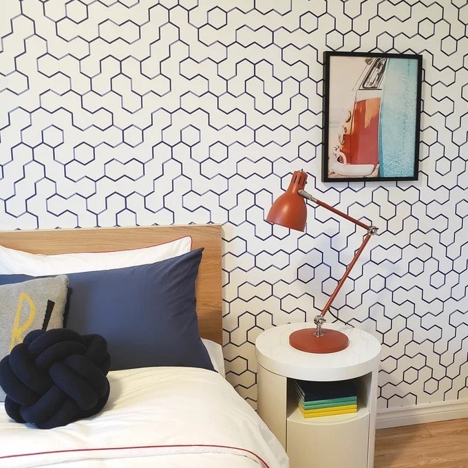 A reviewer photo of the blue and white wallpaper with a geometric pattern on a bedroom wall