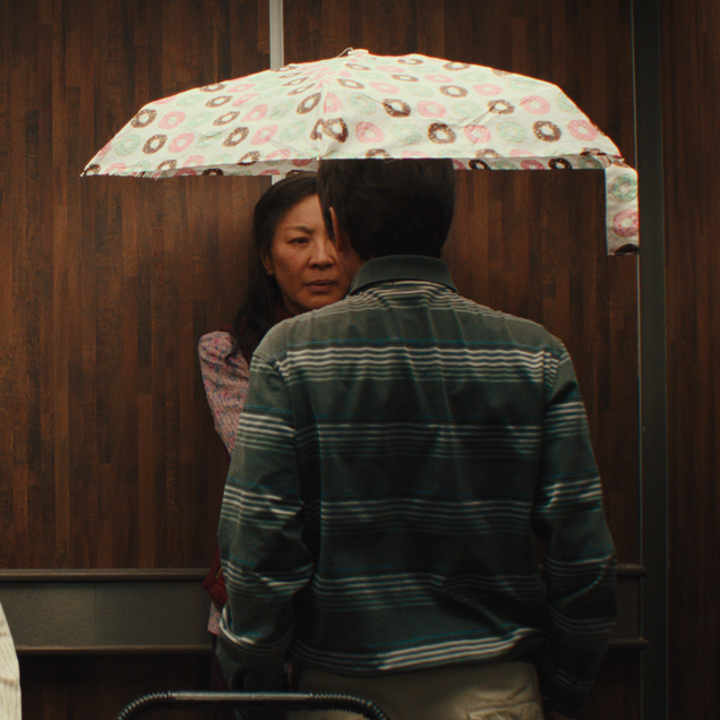 Waymond holding umbrella on top of himself and Evelyn