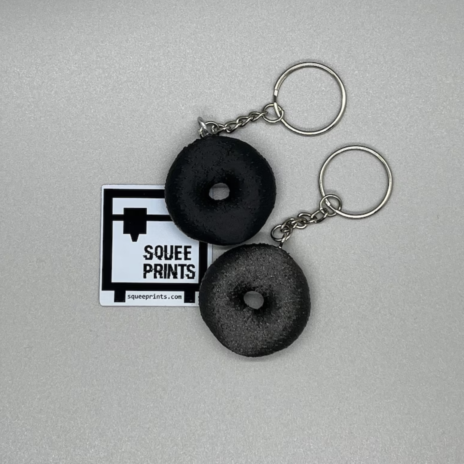 Two everything bagel keychains on a grey background