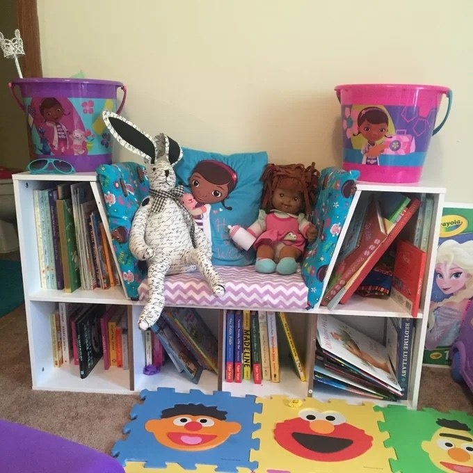 the bookcase in white with plenty of books and toys on it