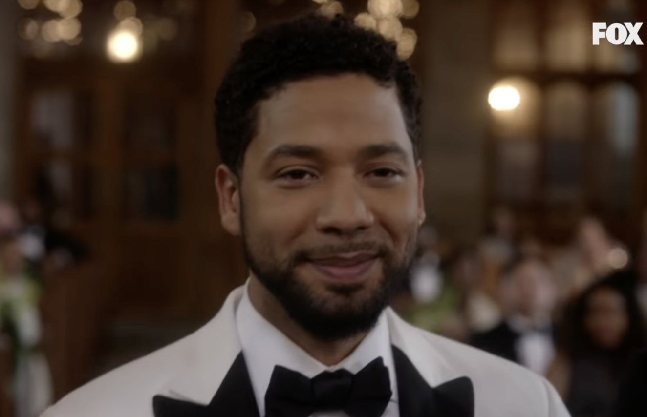 A close up on Jussie Smollett, he&#x27;s smiling and wearing a white tux with a black bow tie