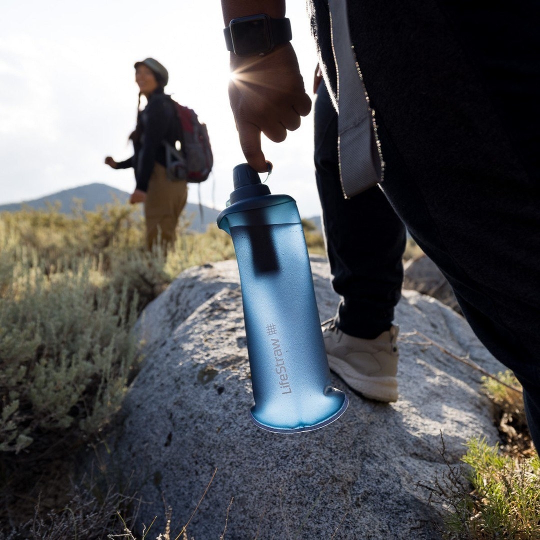 someone toting the foldable water filter bottle on a hike