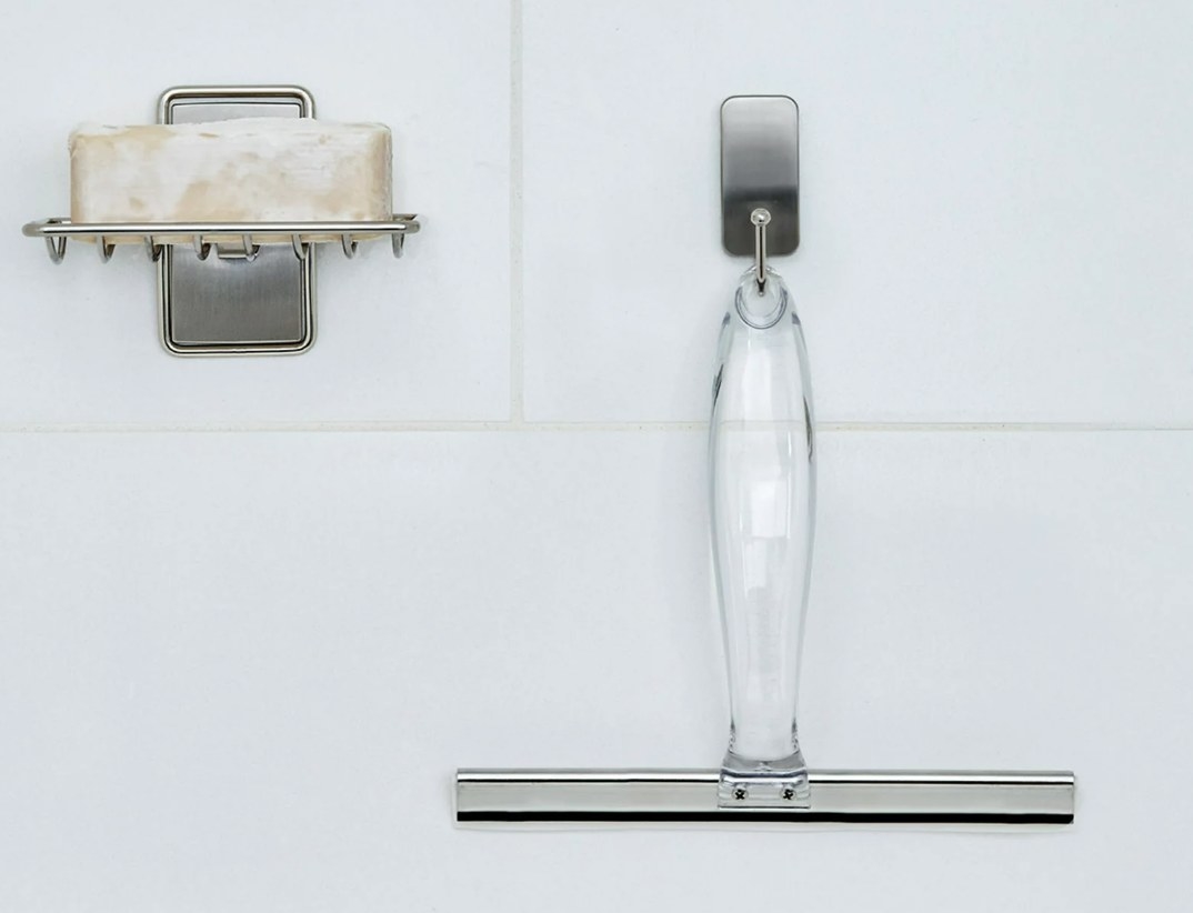 the clear and silver squeegee hanging on a silver hook next to a bar of soap