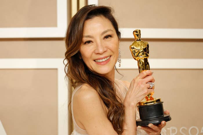 Michelle holding up her Academy Award as she smiles for the camera