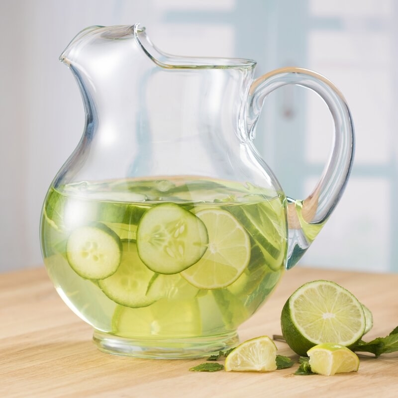 the glass pitcher with a curved spout with cucumber water inside