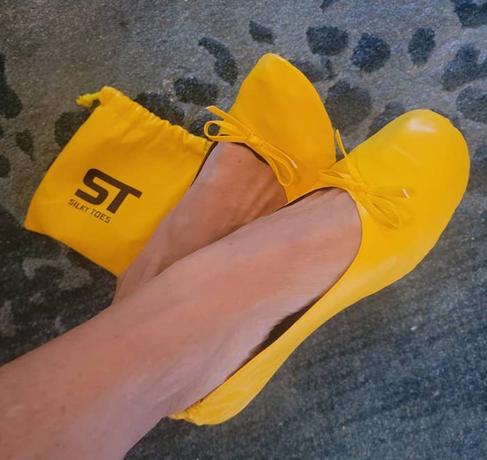 a reviewer wearing the yellow flats next to the carrying case