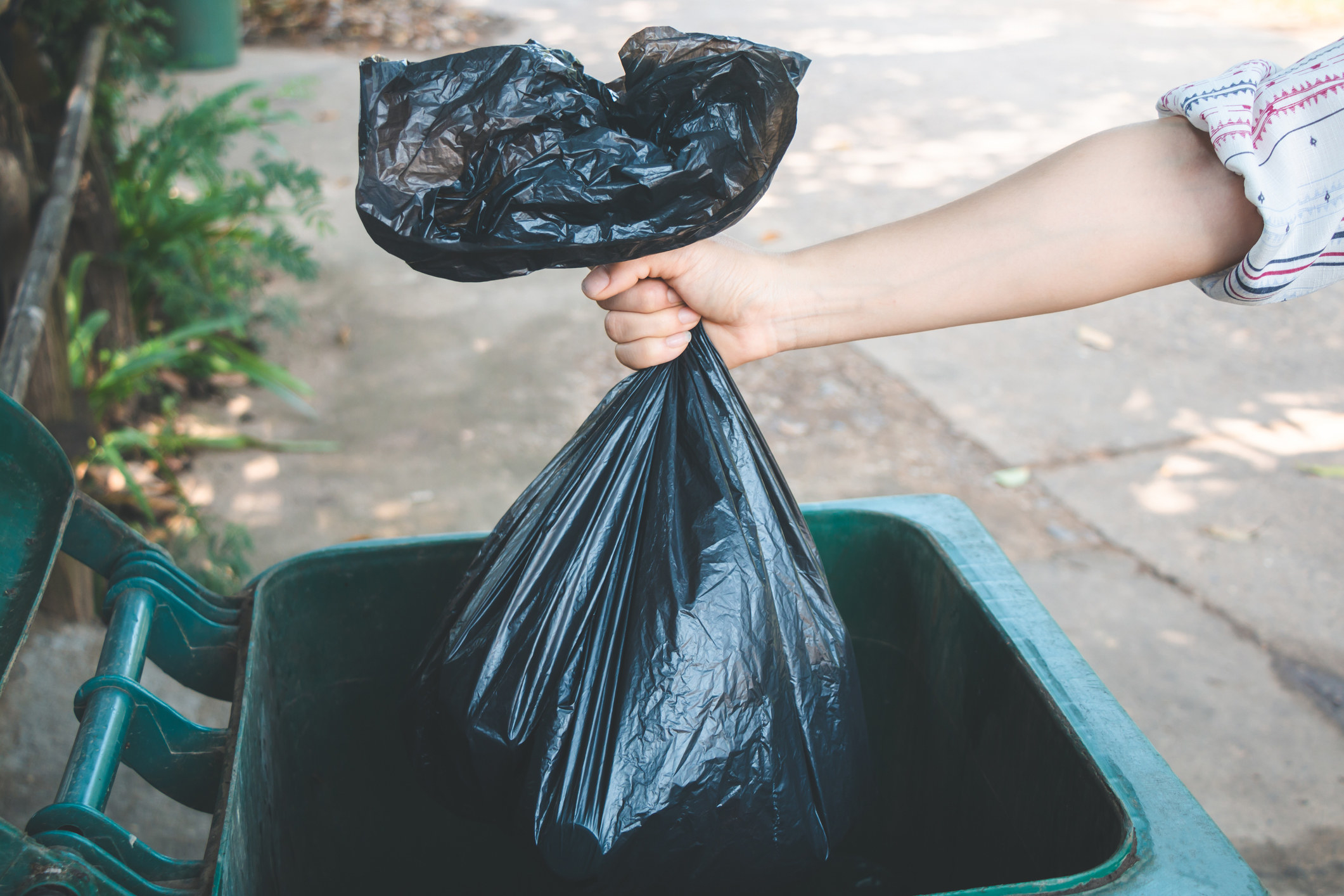 hand placing a trash bag in the bin