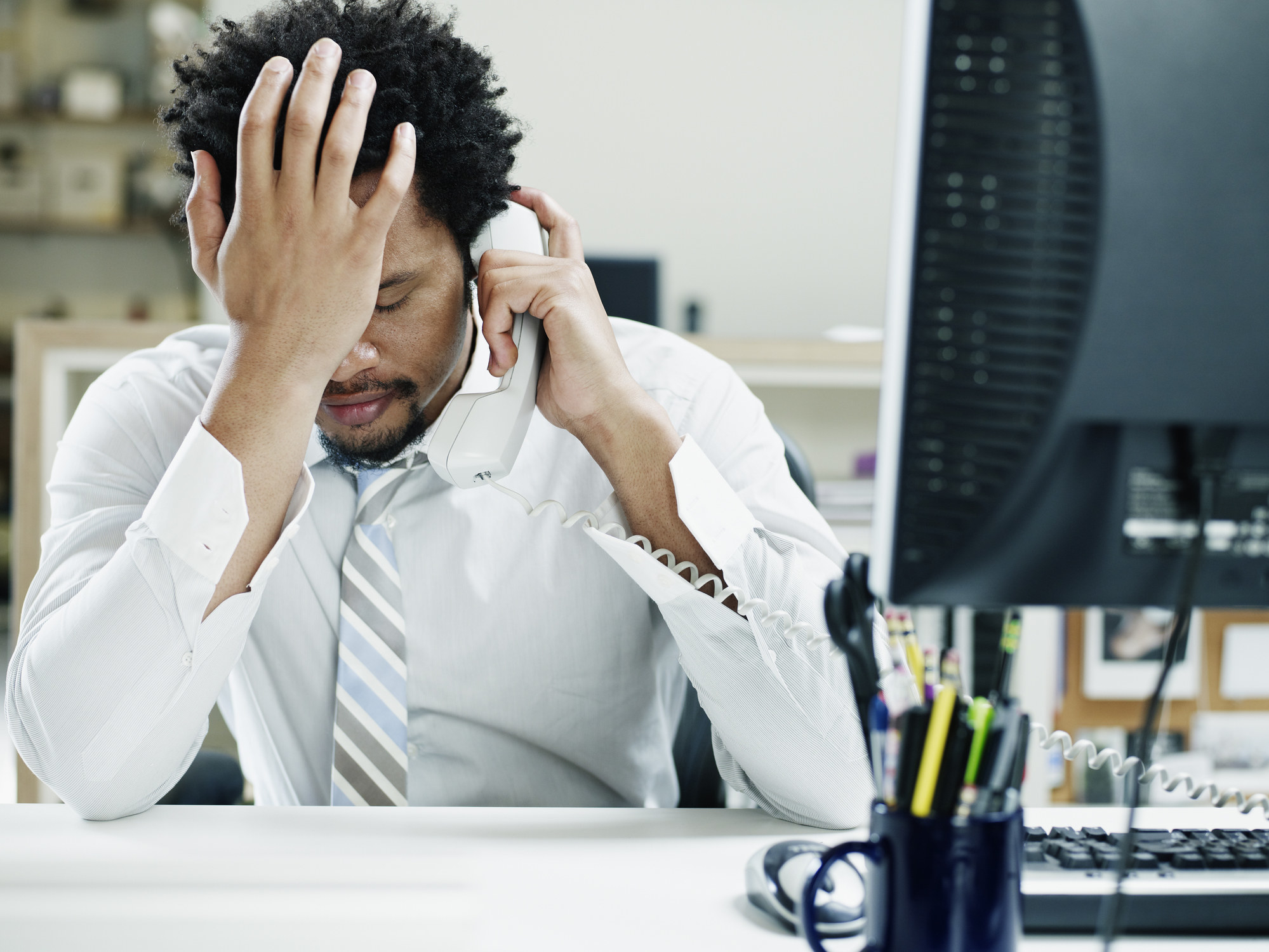 man frustrated at his desk with his head in his palm