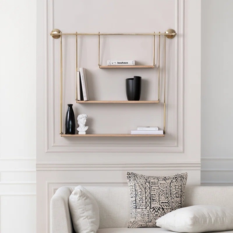 a gold and wood shelf hanging on a wall