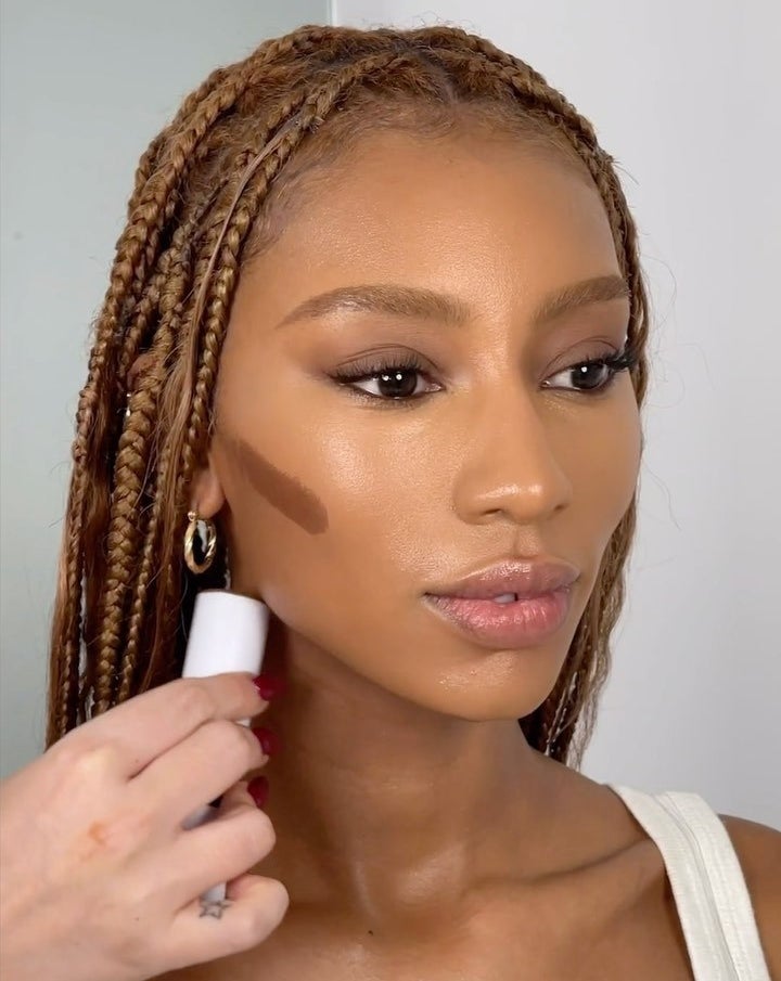 A person applying the product to someone&#x27;s cheekbone