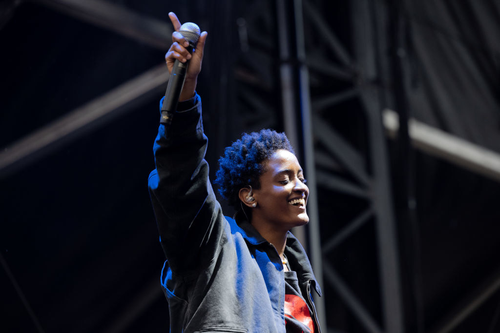 Syd of The Internet performs onstage lifting her arm and holding a mic in Los Angeles, California.